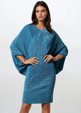 Woman wearing a blue textured dress with a white background